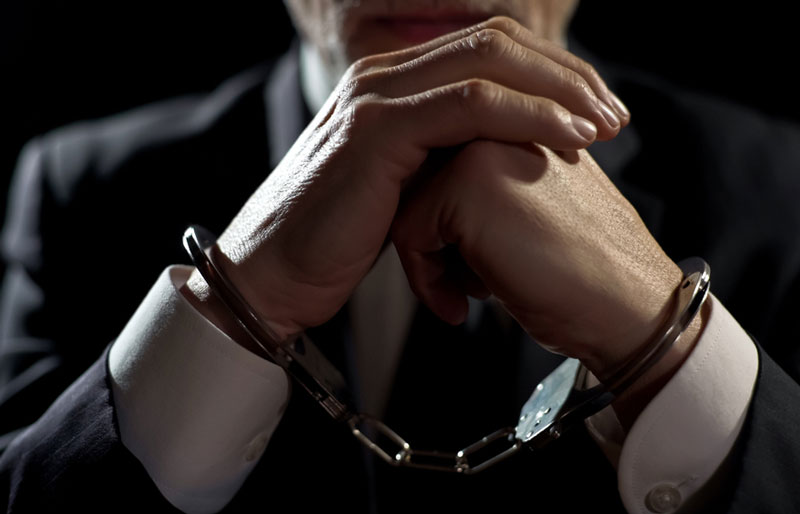 Close up of a businessperson wearing handcuffs.