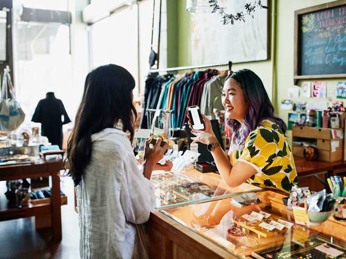 Smiling shop owner helps client at counter in shop 