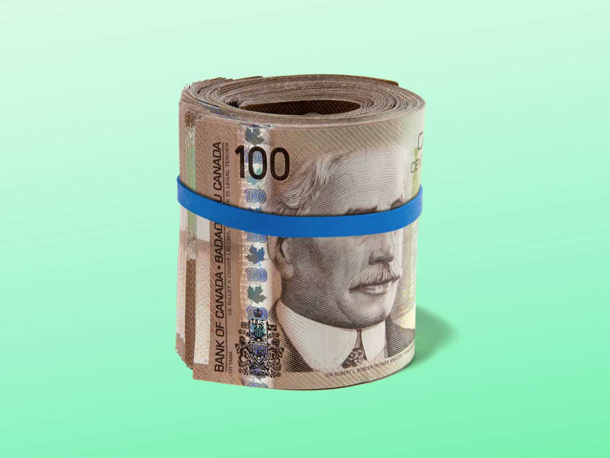 Un rouleau de billets de 100 $ canadiens entourés d'un élastique qui couvre les yeux du visage sur le billet