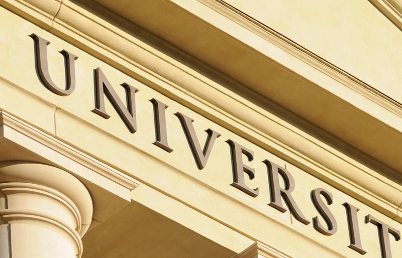 Gros plan sur le mot « université », inscrit sur le fronton d’un bâtiment à l’architecture majestueuse.