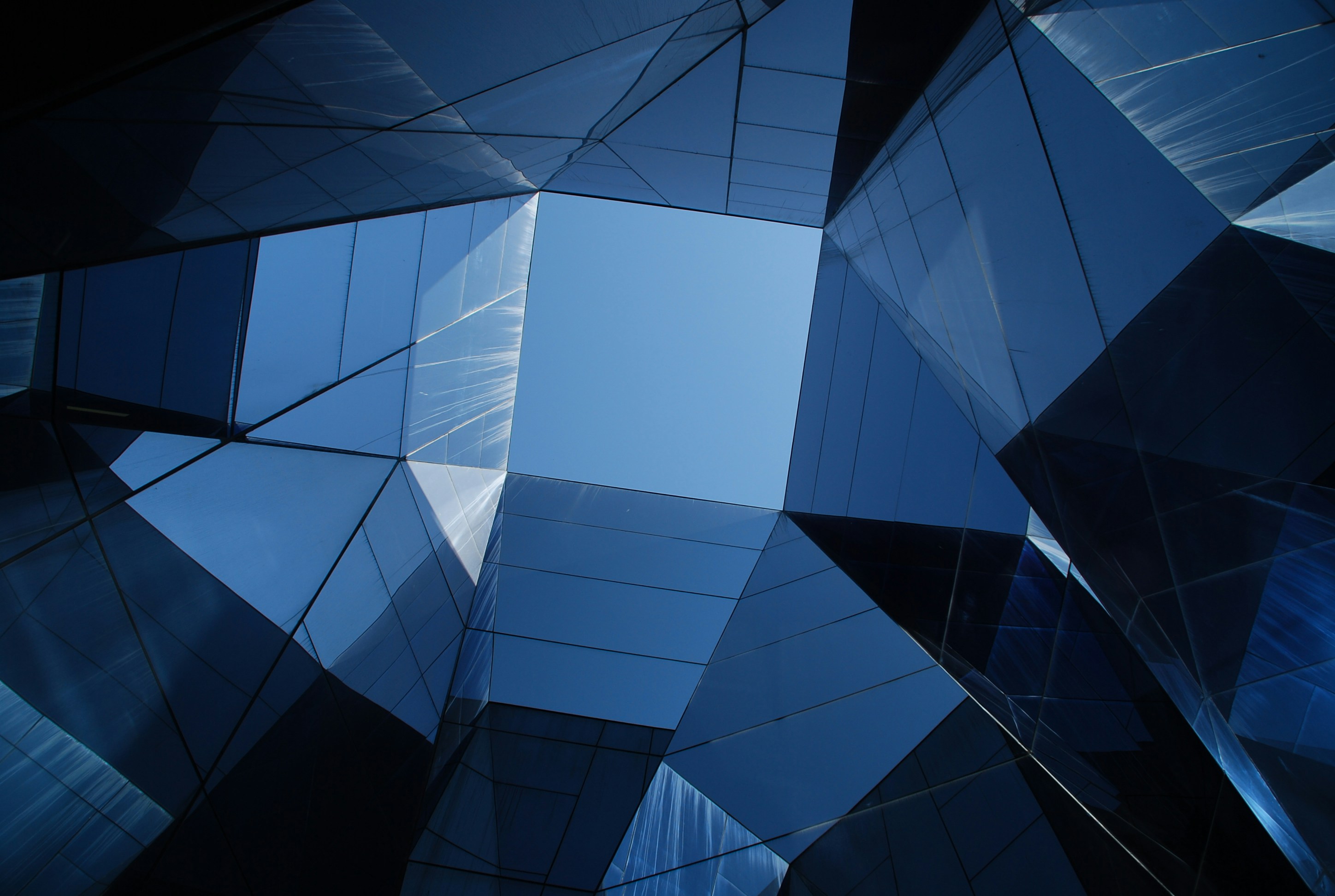 Abstract view looking up at modern glass buildings reflecting the blue sky